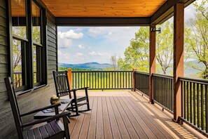 A wooden deck with a view of mountains and trees.
