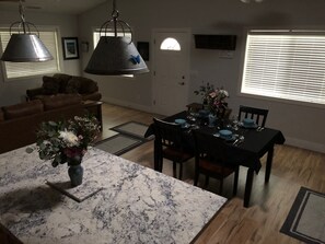 Un espace repas comprenant une table en marbre, des chaises et un luminaire suspendu.