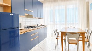 Een moderne keuken met blauwe kastjes, een houten eettafel en stoelen.