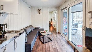 Eine moderne Küche mit Einbauherd, einem grauen Sofa und einem Glastisch.