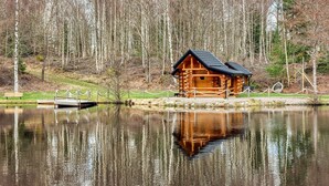 Eine Holzhütte am Ufer eines ruhigen Sees, umgeben von Bäumen.