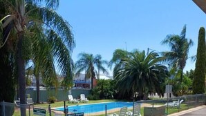 Zona de piscina amurallada con sillas de descanso, palmeras y un cartel que indica que es solo para huéspedes del motel.