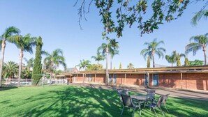 Un motel con césped, mobiliario exterior y palmeras.
