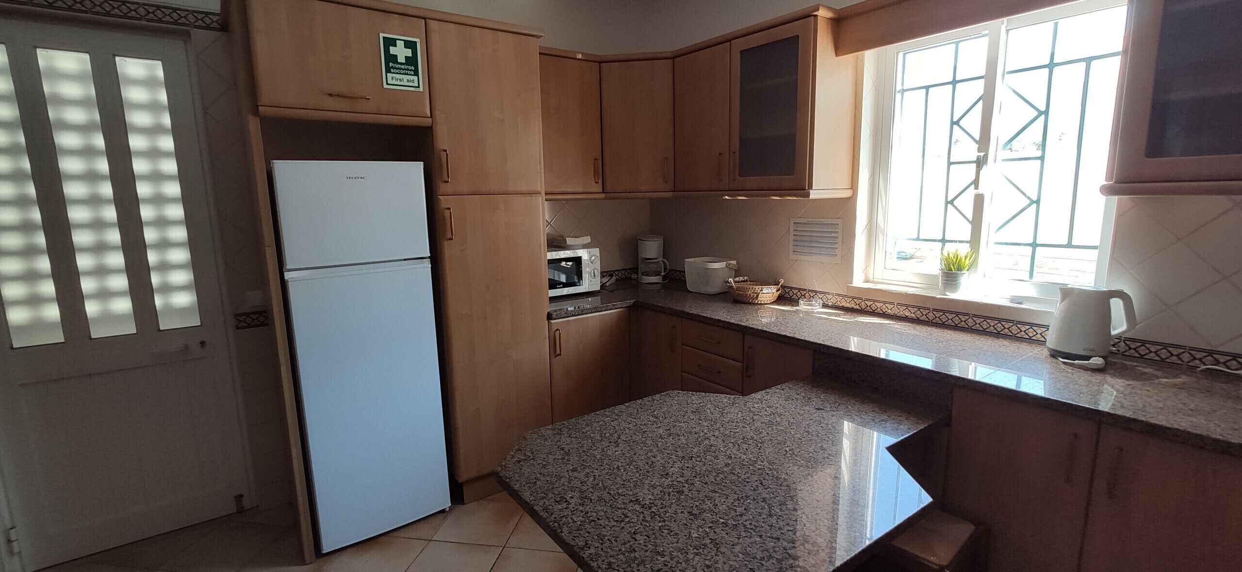 A kitchen with wooden cabinets, a refrigerator, a microwave, and a coffee maker.
