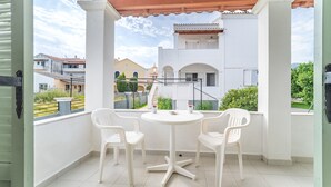 A balcony with a white table and chairs, a view of buildings, and a tiled floor. - Studio Apartment 'Olivea 2' with Sea View, Wi-Fi and Air Conditioning (Kerkira)