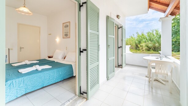 A hotel room with a bed, a desk, and a view of greenery. - Studio Apartment 'Olivea 2' with Sea View, Wi-Fi and Air Conditioning (Kerkira)