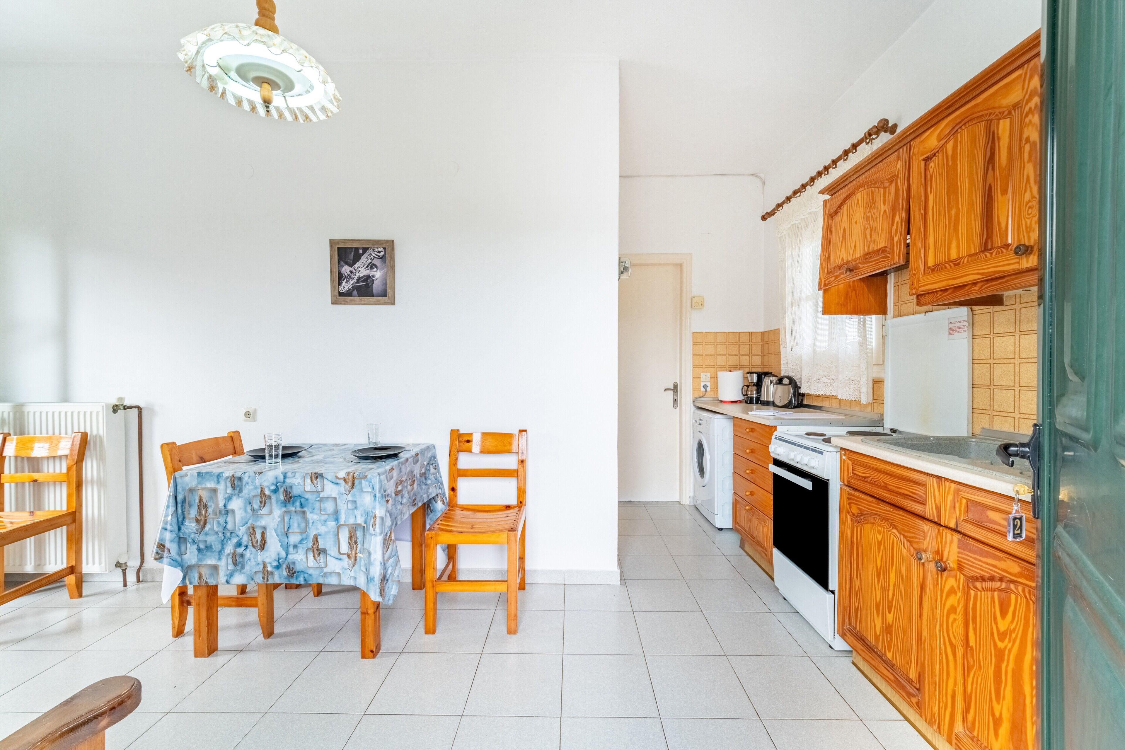 A dining area with a table and chairs, a kitchen with wooden cabinets, and a radiator.