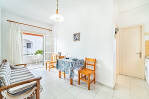 Una habitación con una cama, una mesa de comedor con sillas, un candelabro, una puerta y una lavadora.
