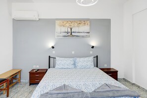 A bedroom with a bed, bedside tables, a desk, and a painting on the wall.