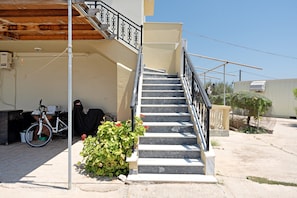 A staircase leading to a building with a metal railing, a bicycle, and a potted plant.