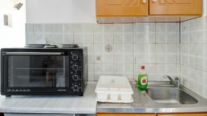 Et køkken med en sort tostovogn, en hvid plastbeholder, en flaske opvaskemiddel og en rustfrit stål vask.