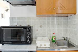 A kitchen with a black toaster oven, a white plastic container, a bottle of dish soap, and a stainless steel sink.