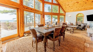 A spacious dining area with a wooden table and chairs, large windows offering a view of the outdoors, and a cozy seating area with a fireplace.