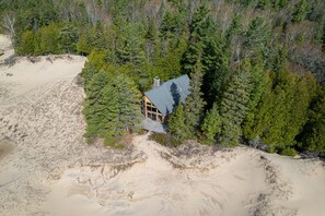 Eine Hütte, umgeben von dichtem Wald und Sanddünen.