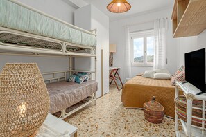 Ein Zimmer mit Etagenbetten, einer gewebten Lampe, einem Fernseher und einem Vorhangfenster.