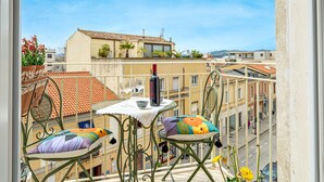 Un balcon avec une table, des chaises et une bouteille de vin.