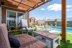 Ein überdachter Außenbereich mit Pool, einer Couch und einem Tisch.
