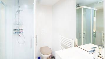 A modern bathroom with a glass shower enclosure, a toilet, a sink with a mirror, and a towel rack.