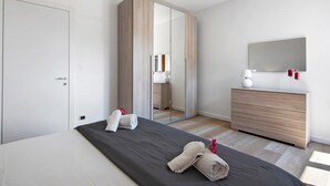 Een moderne hotelkamer met een groot bed, een kledingkast, een dressoir en een spiegel.