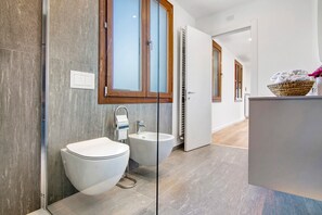 A modern bathroom with a toilet, bidet, and a mirror with wooden frames.