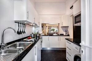 Een moderne keuken met roestvrijstalen apparatuur, een dubbele spoelbak en een Bosch wasmachine.