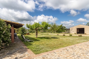 A patio with stone flooring, a brick structure, and a table with chairs.
