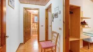 Ein Flur mit einem Holzstuhl, einer Holztür und einem Bett mit weißer Bettdecke.