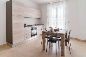 Een koelkast, een oven, een kookplaat, kookgerei, borden en bestek
