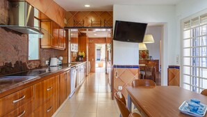 A kitchen with wooden cabinets, a stainless steel range hood, and a dining area with a table and chairs.