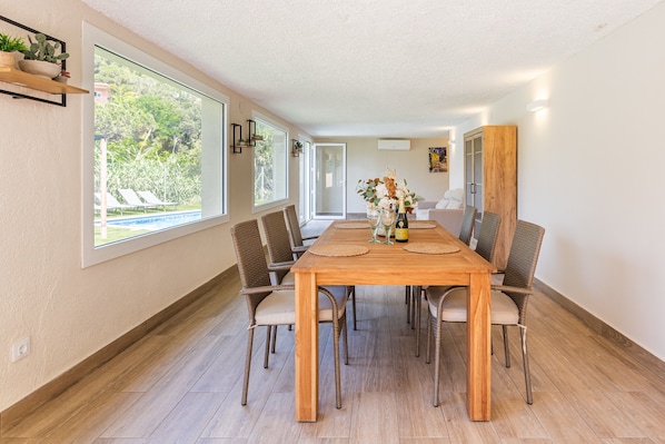 Un coin repas avec une table en bois, des chaises en osier et une vue sur la verdure environnante.