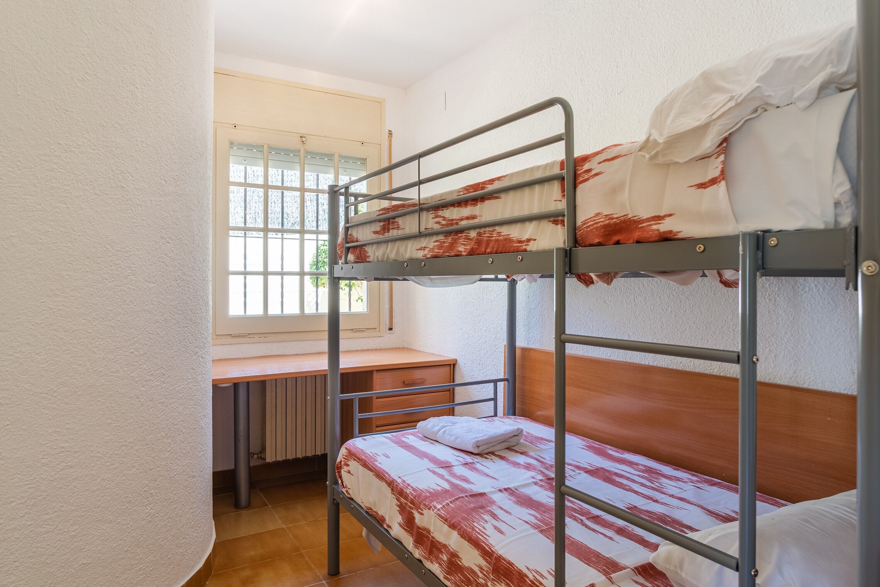 A bunk bed room with a desk and radiator.