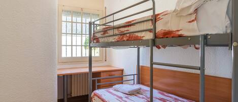 Quarto com beliche, escrivaninha e radiador.