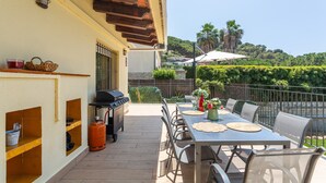 An outdoor patio with a dining table, chairs, a grill, and a gas cylinder.