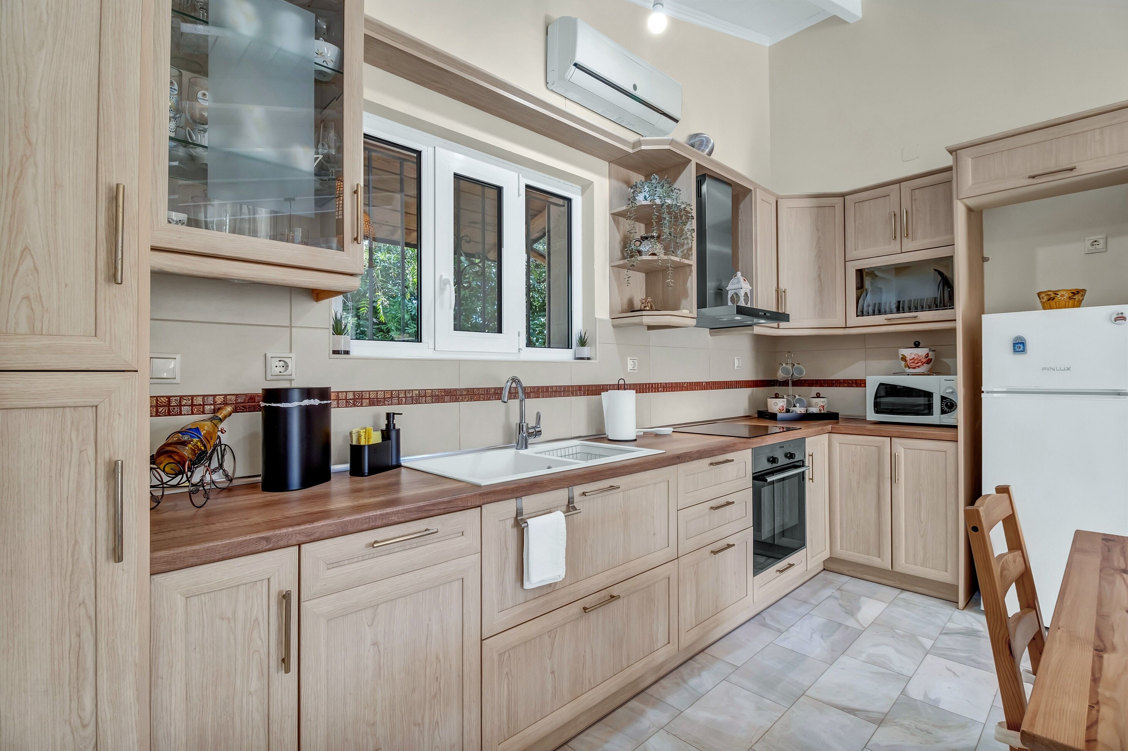 A kitchen with wooden cabinets, a double sink, a microwave, and a refrigerator.