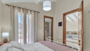 Une chambre à coucher avec un lit, des rideaux, une lampe de chevet, un miroir et une vue sur une autre pièce.