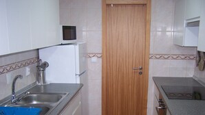 A compact kitchen with a sink, a microwave, and a small window above the door. - Apartment 'Moradia Machado' with Private Terrace, Balcony and Wi-Fi (Topo Calheta São Jorge Açores)