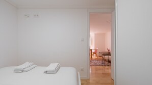 Une chambre avec un lit bien fait, une petite table et une chaise dans la pièce adjacente.