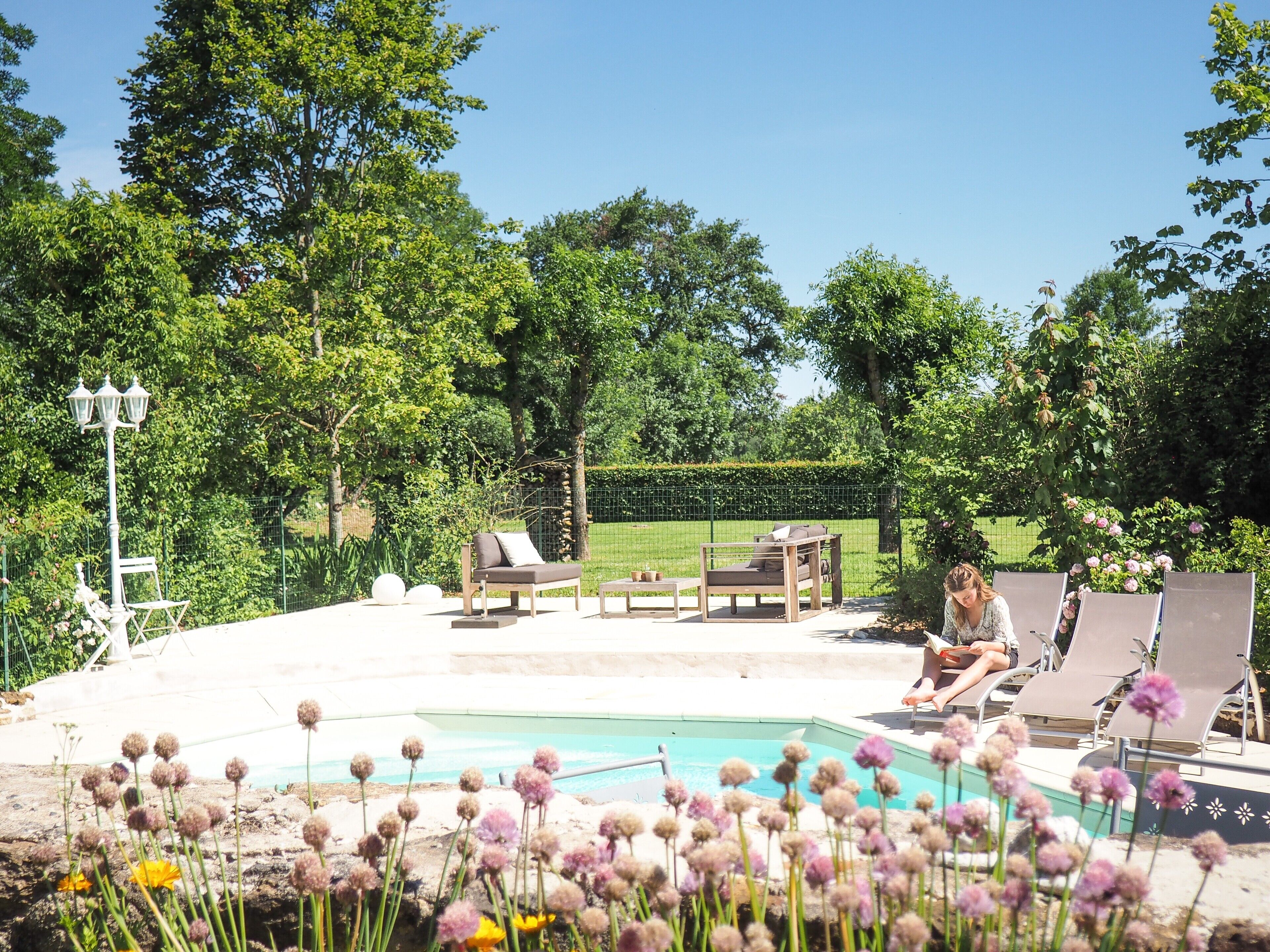 An outdoor pool area with lounge chairs, a table, and a lamp post.