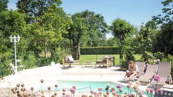 An outdoor pool area with lounge chairs, a table, and a lamp post.