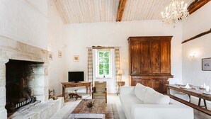 Een woonkamer met een open haard, bank, houten kast en een kroonluchter.