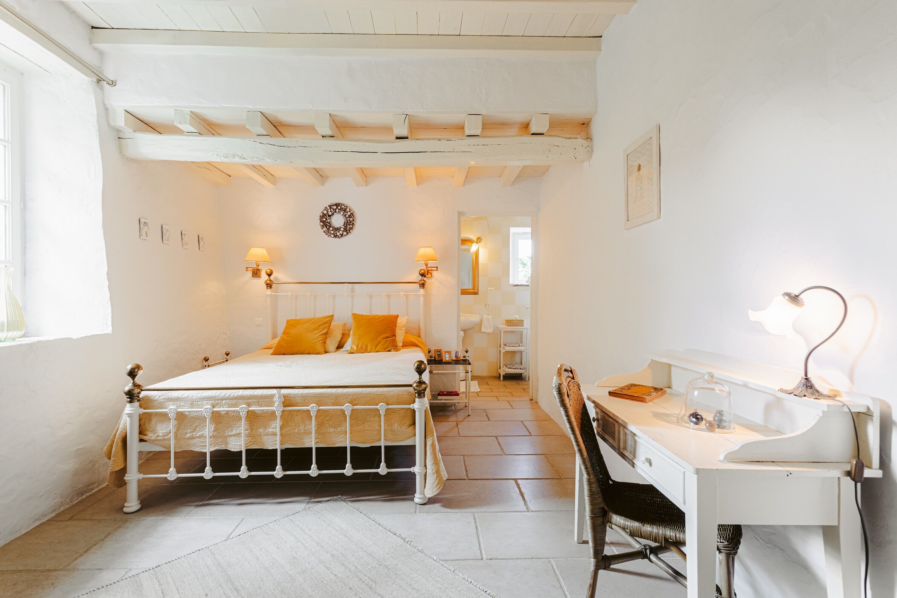 Ein Schlafzimmer mit Bett, Schreibtisch, Stuhl und einem kleinen Tisch mit Lampe.