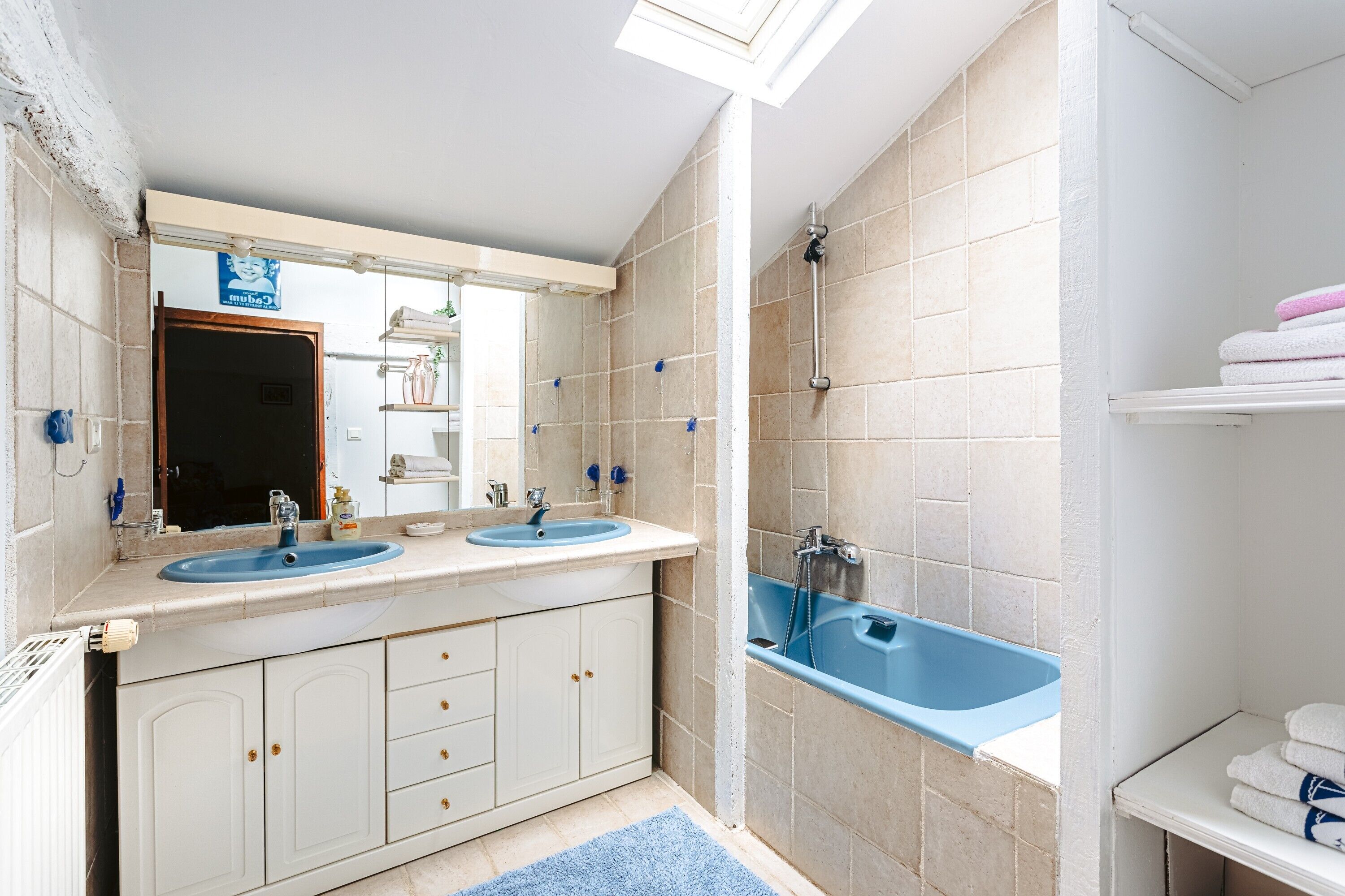 Une salle de bain avec deux lavabos, une douche et une fenêtre de toit.