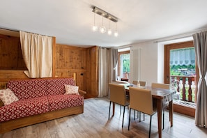 Un intérieur en bois comprenant un canapé, une table à manger, des chaises et un balcon avec vue.