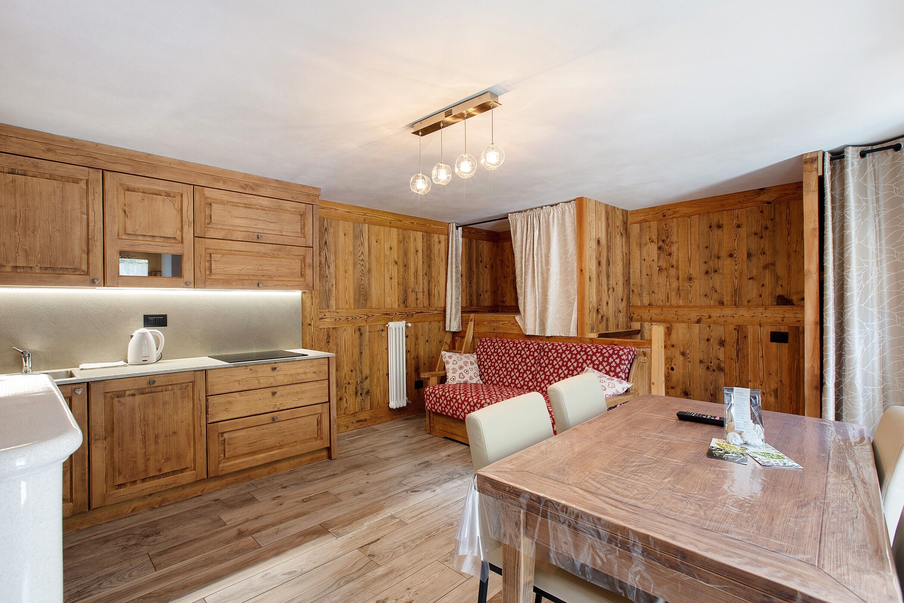 Une cuisine en bois équipée d’un évier, d’une bouilloire et d’une table à manger avec des chaises.