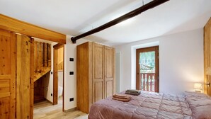 Un dormitorio con un armario de madera, una cama con colcha rosa y vistas a un balcón.