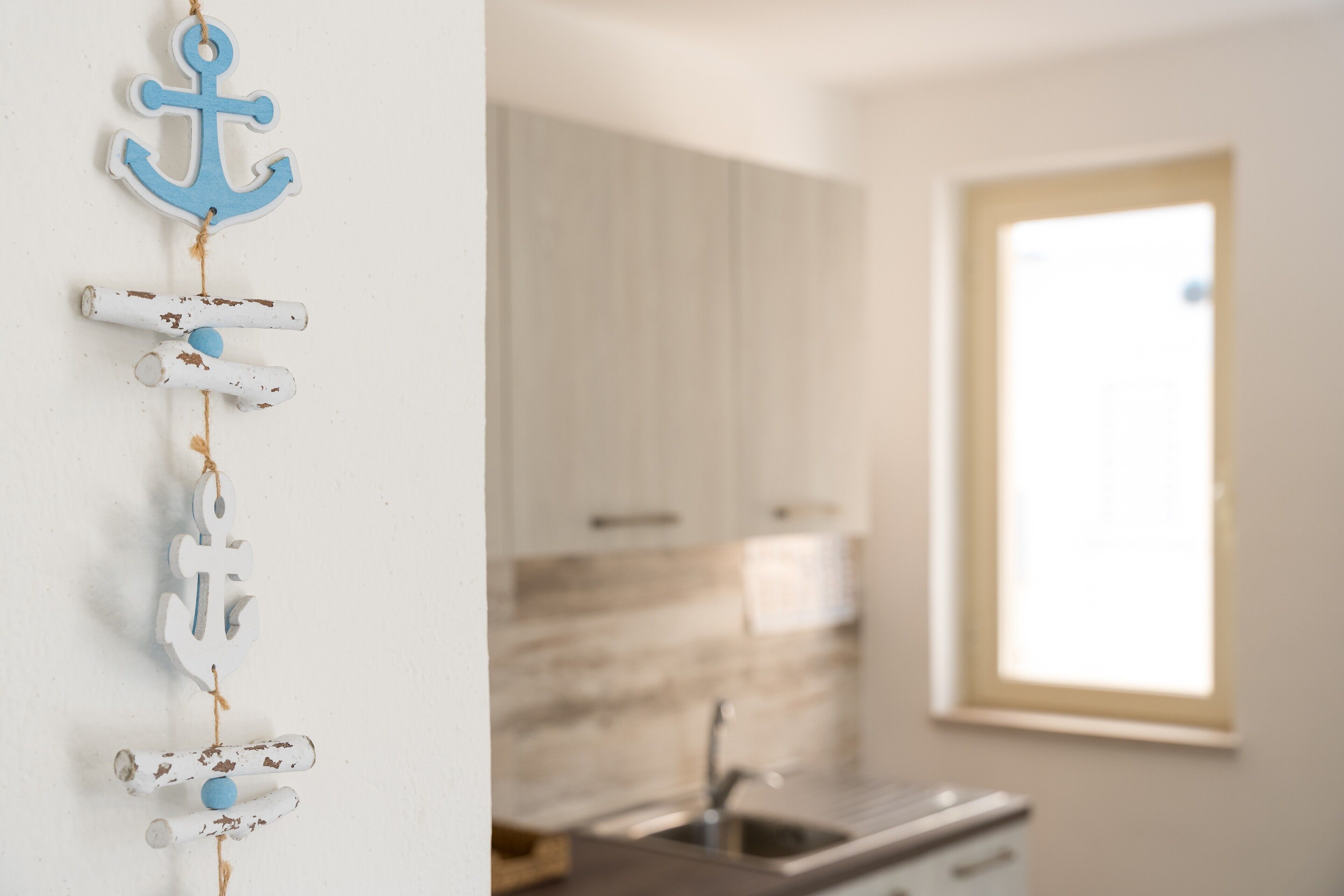 Una cucina con finestra, pensili e una decorazione appesa.