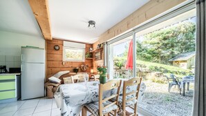 A kitchen with a refrigerator, a dining table with chairs, and a window with a view of the outdoors.