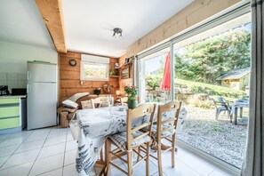 Een keuken met een koelkast, een eettafel met stoelen en een raam met uitzicht op het landschap.