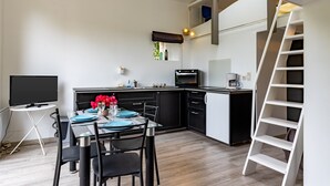 Uma cozinha compacta com área de refeições, uma TV de tela plana e uma escada branca.