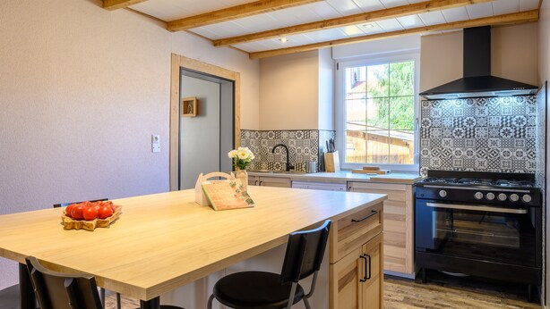 A kitchen with a wooden table, chairs, a stove, and a window. - Holiday Home 'Gîte Les 3 Cerfs - 3 Stars' with Mountain View, Private Terrace & Wi-Fi (Plainfaing)